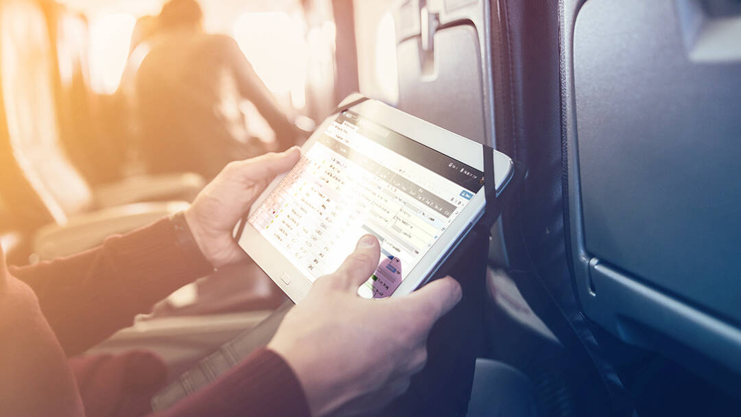A person looks at tablet computer while seated on a commercial airplane.