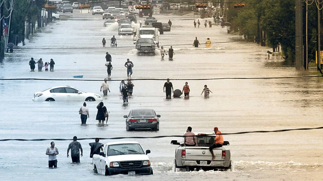 People standing amongst cars on a flooded Houston street.
