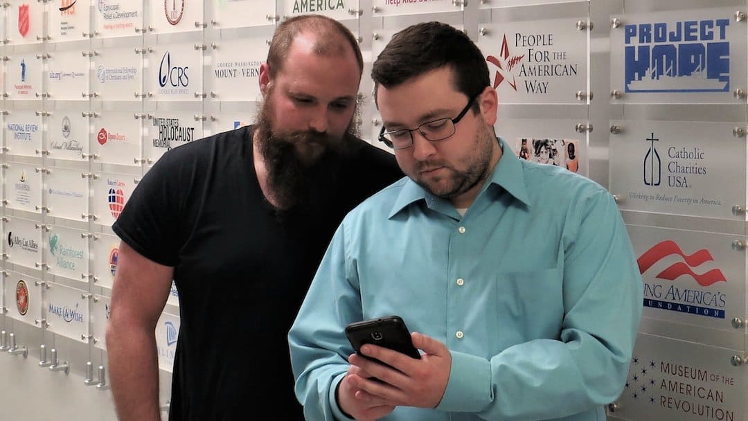 Two Merkle RMG employees look at a smartphone