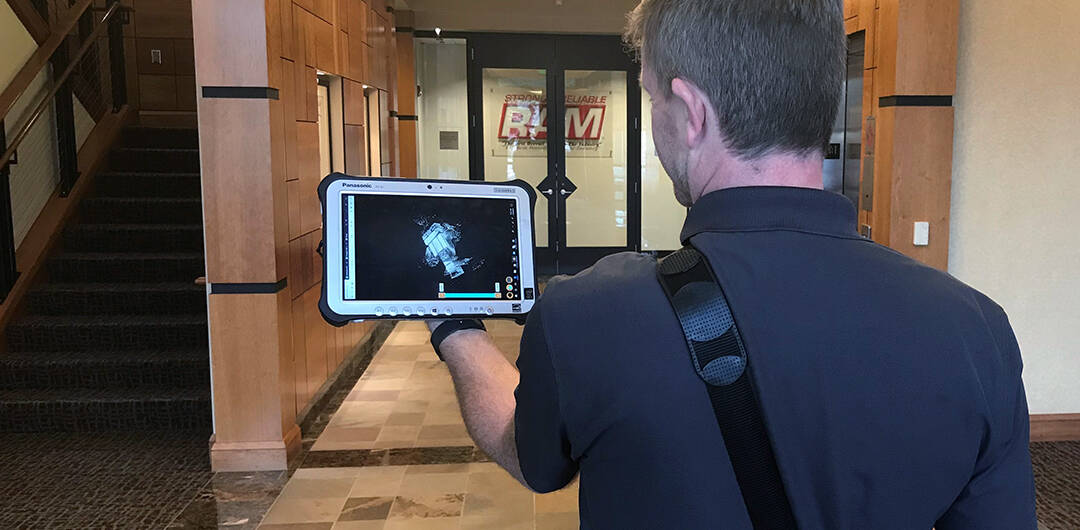 A PM Design Group employee performs a virtual mapping of a building interior with a tablet computer.
