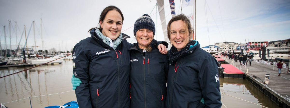 Lou Adams, Pip Hare, and Isla Reynolds stand together smiling at the camera
