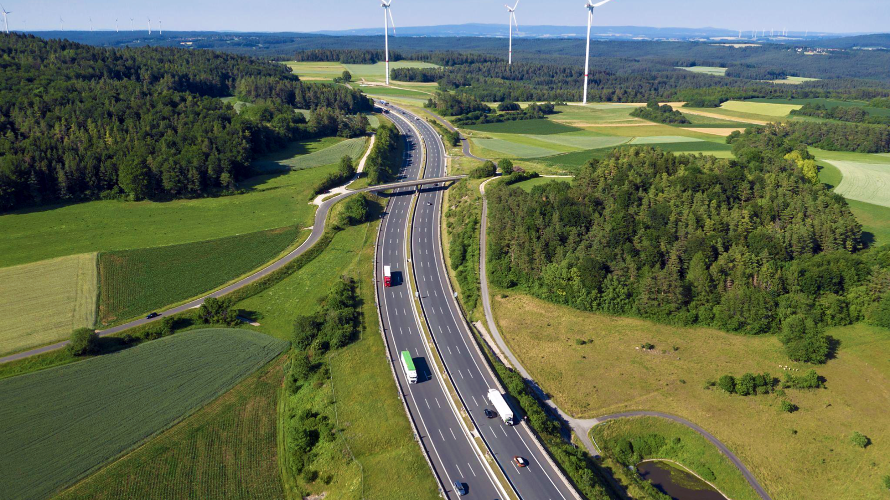 Aerial view of highway, fields and windmills 