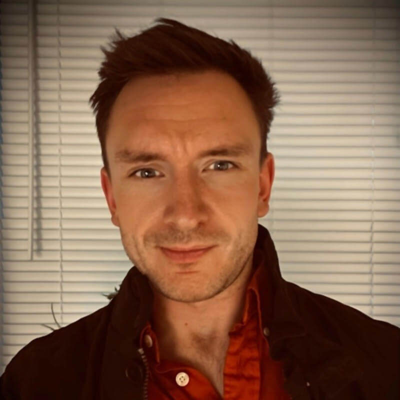 A man with a black and red shirt smiling at the camera