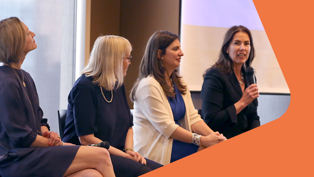 A line of female women dressed in suits while talking at a panel